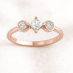Rose gold ring with three diamonds on a light pink background