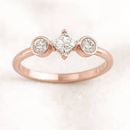 Rose gold ring with three diamonds on a light pink background
