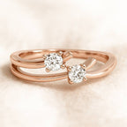 Rose gold ring with two diamonds on a beige background