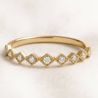 Gold ring with diamond accents on a light beige background
