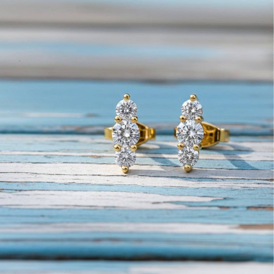 gold earrings with clear gemstones on a soft wood background