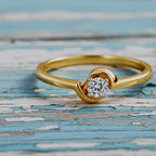 Gold ring with a diamond on a wood background