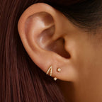 Close-up of an ear wearing gold earrings with a blurred background