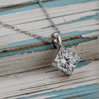 Gold necklace with a square-cut diamond pendant on a wood background