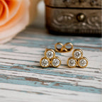 Pair of earrings with three circular gemstones on wood background