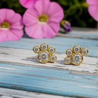 Pair of yellow gold earrings with circular diamonds on a light pink background