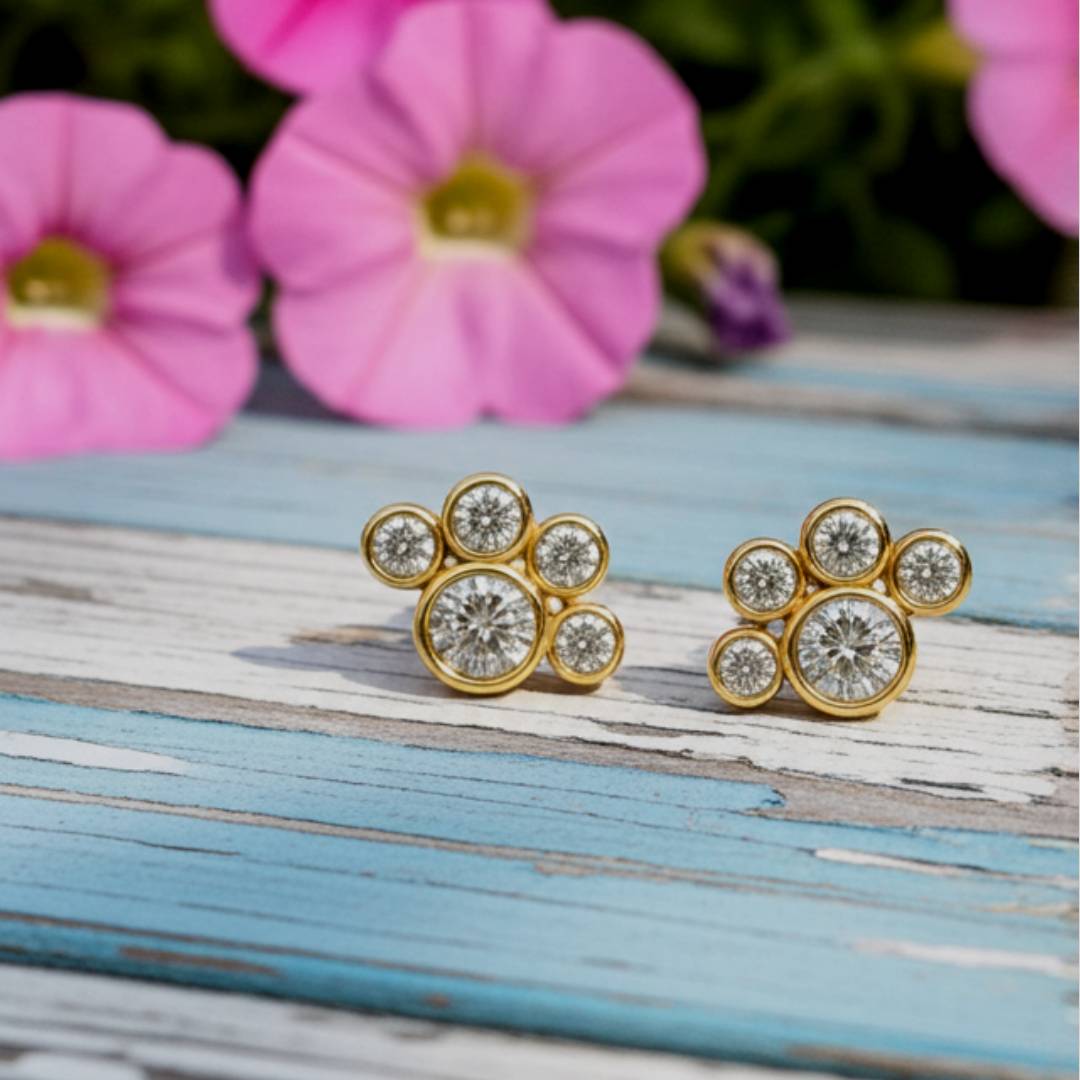 Pair of yellow gold earrings with circular diamonds on a light pink background