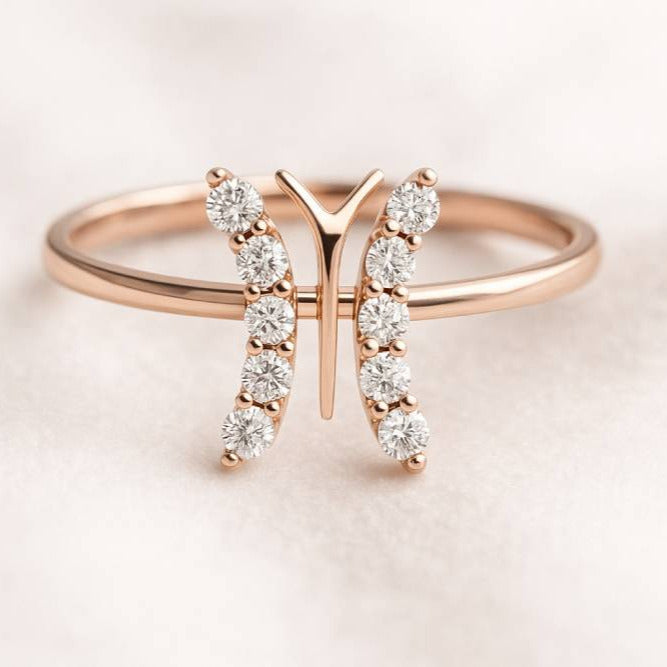 Rose gold ring with diamond accents on a light pink background