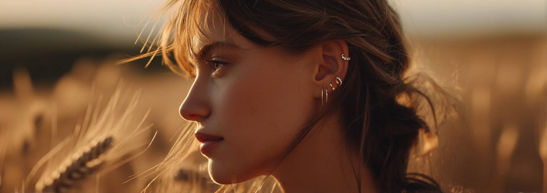 Woman with a side profile in a field of tall grass during sunset.