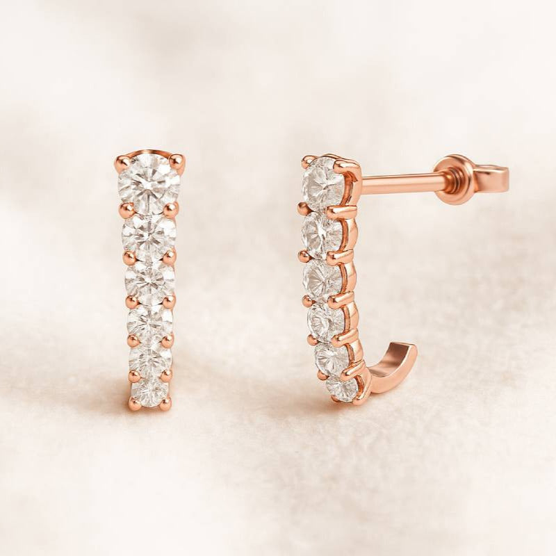 Rose gold hoop earrings with clear gemstones on a beige background