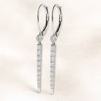 Pair of diamond earrings on a light pink background